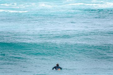 Fototapeta na wymiar Surfer patiently waiting for the perfect wave