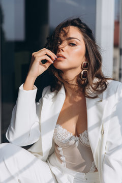 Beautiful young sexy woman, glamour girl in the white elegant jacket, corset, suit, makeup pastel tone lipstick, nails on the office balcony with the urban background.