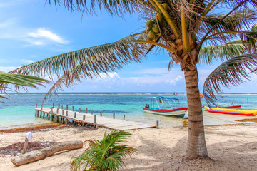 Beautiful tropical beach with turquoise water, a pier and a colorful boat at Mahahual, Mexico