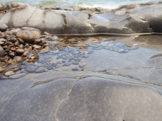 Coloured stones in the sea water with reflexes and waves on the background