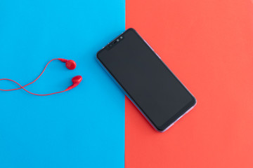 Black Smartphone with Red Handsfree on a Red and Blue Background