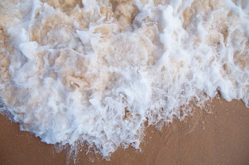 Fototapeta na wymiar View from above on water froth, foam from wave on sand