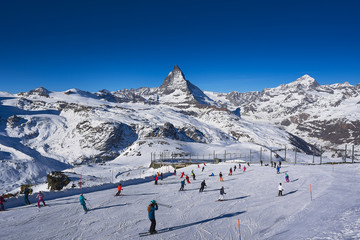 Fototapeta na wymiar Skiers skiing downhill at Gornergrat with Matterhorn view in background.
