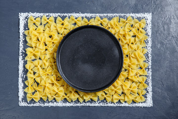 Border of a pile of pasta bow on dark black background with copyspace