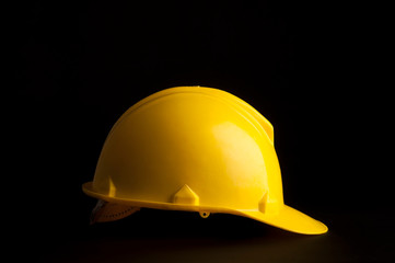 Yellow safety worker helmet on black background.