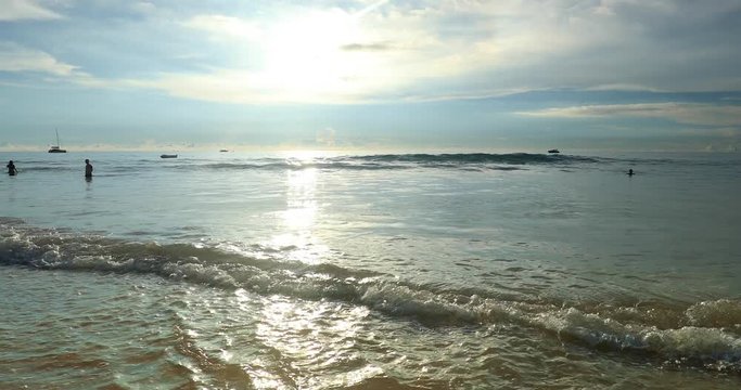 Indyllic beach with brigh sunlight and calm water waves rolling on sand shore