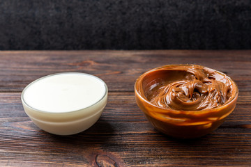 Boiled condensed milk on dark wooden background.