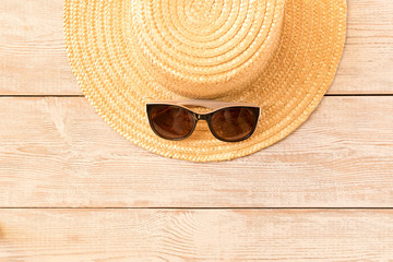 Fototapeta na wymiar Sunglasses and a straw hat on a wooden table. The concept of summer.