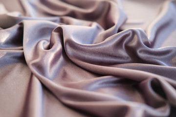 Close up pink fabric. The purple silver fabric is laid out waves. Fuchsia sateen fabric for background or texture.