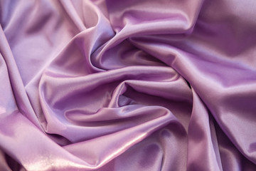 Close up pink fabric. The purple fabric is laid out waves. Fuchsia sateen fabric for background or texture.