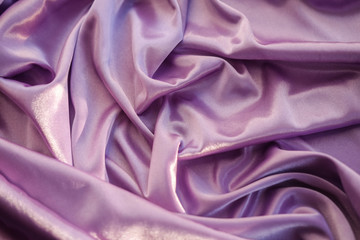 Close up pink fabric. The purple fabric is laid out waves. Fuchsia sateen fabric for background or texture.