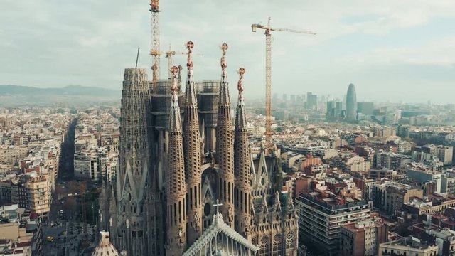 Aerial; drone view of main Barcelona attraction; majestic building towering over the rooftops of Eixample district; long construction of temple "business card" of Catalonia, Spain; camera moves around