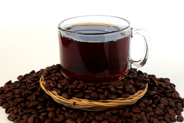 dark roasted coffee beans with coffee cup closeup on white background