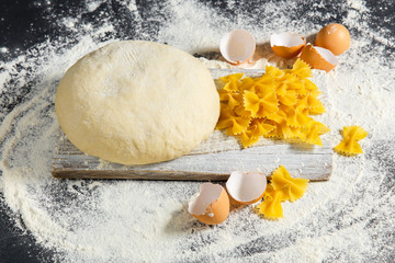 Pizza dough or baking on a dark black background of wood. Baking bread, pizza, pasta. Top view, horizontal photo