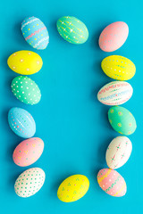 Colorful Easter eggs frame on blue background top view space for text