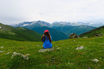 Tourist girl sitting and looking at the mountains