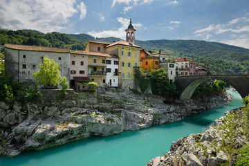 Colorful stucco houses on the turquoise Soca River with stone bridge at old section of Kanal...