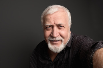 Obraz premium good-natured charismatic man on a gray background makes a selfie on the camera