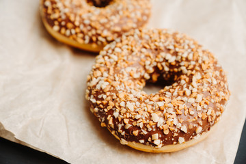 Donut with chocolate glaze and crashed nuts on the rustic background. Selective focus.