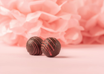 Round chocolates on a gentle coral background. Copy space. Selective focus. Horizontal frame.