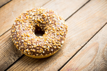 Donut with chocolate glaze and crashed nuts on the rustic background. Selective focus.