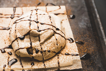 Chocolate meringue dessert decorated with glaze and chocolate powder. Selective focus.