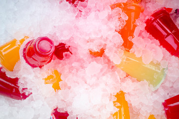Orange juice and colorful sweet water on ice crystals