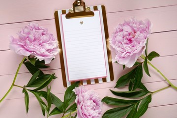 Spring floral Flat lay.Spring to-do list.pink peonies flowers and blank clipboard on pink board background.top view, copy space. Mothers Day. International Women's Day.