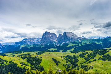 Naklejka na ściany i meble Alpe di Siusi, Seiser Alm with Sassolungo Langkofel Dolomite, a large green field with a mountain in the background