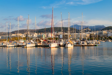 Fototapeta na wymiar Beautiful cityscape port, arsenal, modern buildings, yachts, azure sea water on the background of stormy sky at evening, harbour of Rethymno, island of Crete, Greece, Southern Europe.