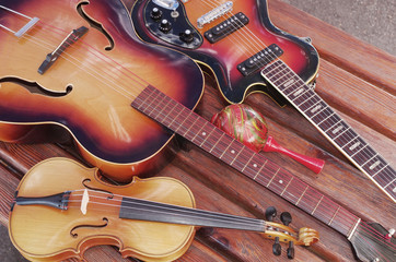 Acoustic guitar, violin, maracas, fife and red rose on a wooden table.