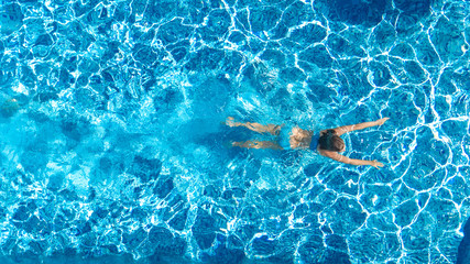 Active girl in swimming pool aerial drone view from above, young woman swims in blue water, tropical vacation, holiday on resort concept
