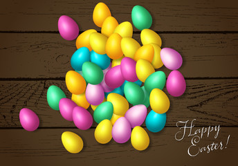 Easter frame with shiny colorful happy eggs spread over wooden background