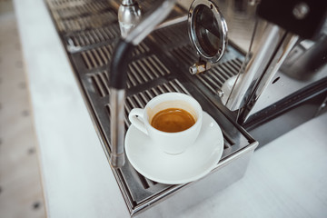 close-up view of glass cup with cappuccino and coffee machine