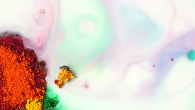 Close-up of colorful red, yellow, orange and green pigments on a white liquid surface. Colorful concept.