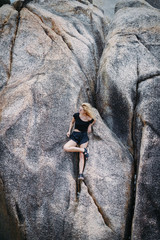 blonde girl sitting on a rock formation by the beach in Thailand