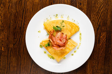 crepes with bacon ont he wooden background, top view