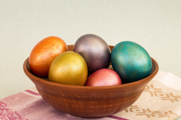 Fototapeta na wymiar bright colored Easter eggs (pink, blue, orange, yellow, purple) in bowl closeup; marble texture, neon colors, shiny paint
