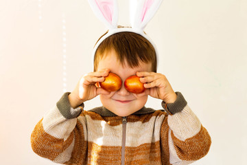 boy in easter bunny costume has fun with easter eggs