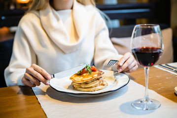 Young woman having breakfast and cut pancakes