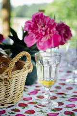 summer garden party table with bread in wicker basket, tasty lemonade and pink peonies