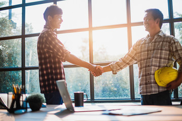 Businessmen, engineers standing shaking hands in the office. - Image