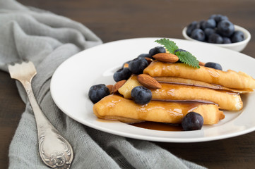 pancakes with syrup nuts and blueberries. on a white plate