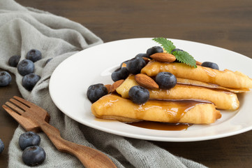 pancakes with syrup nuts and blueberries. on a white plate