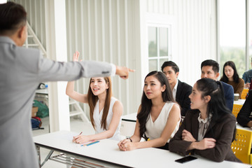Fototapeta premium Asian male speaker is speaking at seminars and workshops to the people in the meeting. Participants are raising their hands to ask questions.