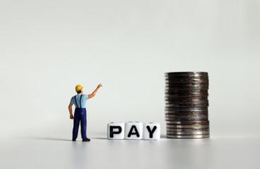 ‘PAY' text in white cube. Miniature people and pile of coins.