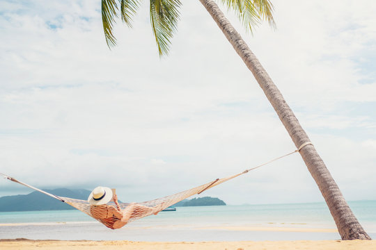 Asian women relaxing in hammock summer holiday on beach