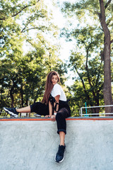 Beautiful young hipster girl sitting on the edge of a ramp