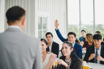 Obraz premium Asian male speaker is speaking at seminars and workshops to the people in the meeting. Participants are raising their hands to ask questions.