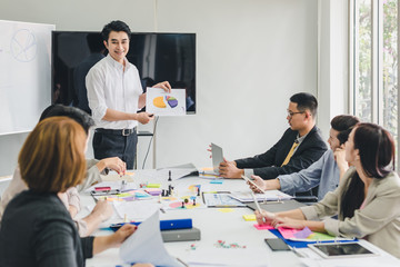 A group of Asian businessmen are discussing. Employees are presenting their work to the meeting.